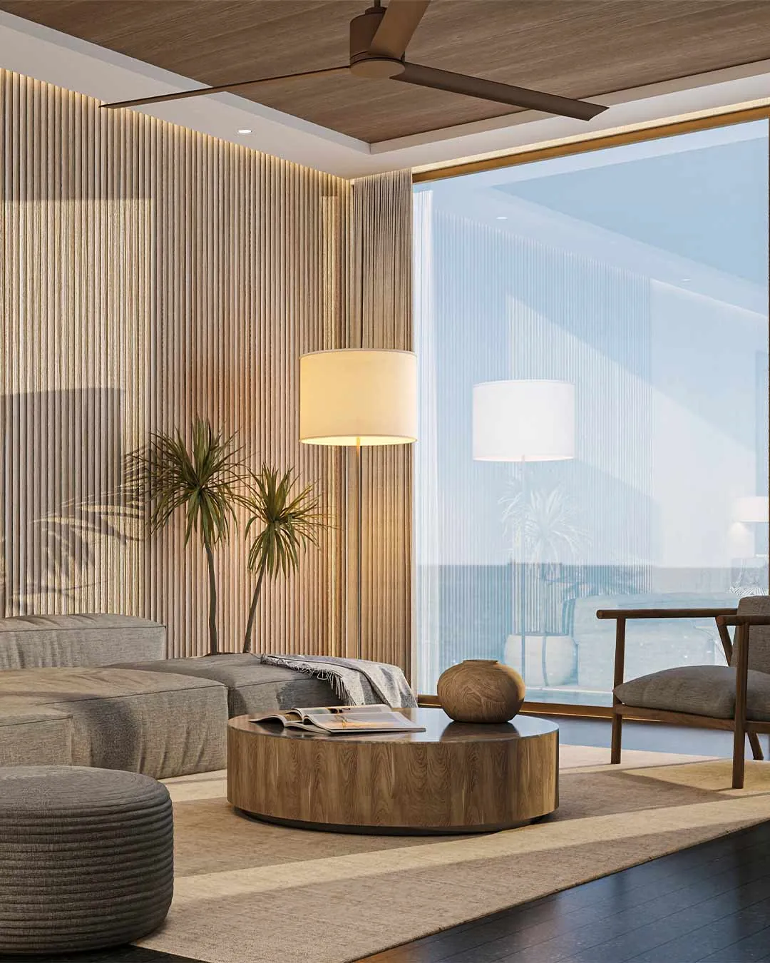 Living room with sofa, round coffee table and floor-to-ceiling windows facing the ocean
